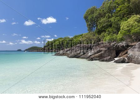 View of rocky coastline with green and turquoise water along Whitehaven Beach in the Whitsunday Islands, Queensland, Australia