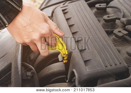 Close-up of the hands The blond girl opens the hood of her car and checks the engine oil level. The concept of car maintenance by women. The concept of a malfunction of the car and its engine