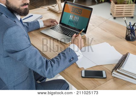 business man sitting at workplace with papers and laptop in office