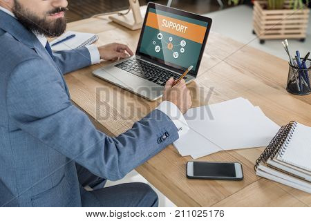 business man sitting at workplace with papers and laptop in office
