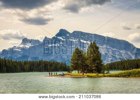 TWO JACK LAKE, ALBERTA, CANADA - JUNE 26, 2017 : Tourists enjoy a sunny day at the two jack lake in Banff National Park with Mt. Rundle in the background.