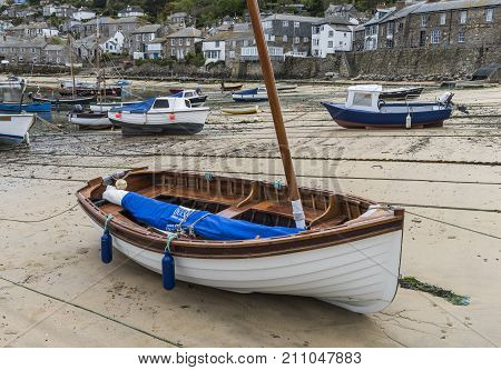 Mousehole England - April 28 2017: Harbor of Mousehole with fishing boats sail boat houses and low tide Cornwall.