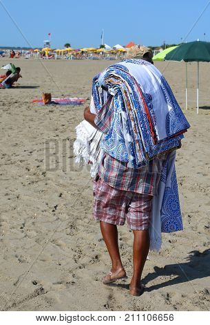 Abusive Street Vendor With Towels And Fabrics On The Beach