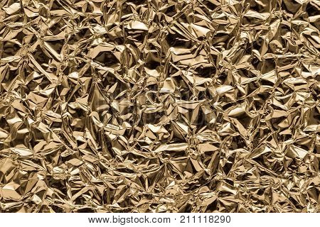 brilliant texture of a crumpled metal foil closeup for an abstract background or for festive wallpaper of bronze color