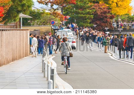 KYOTO JAPAN - NOVEMBER 24 2016 Biker cyclists on a street near the Togetsukyo Bridge and many people come to visit autumn season Arashiyama Kyoto Japan.