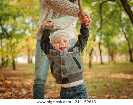 Mom holds his son for crayfish and plays with him in the park