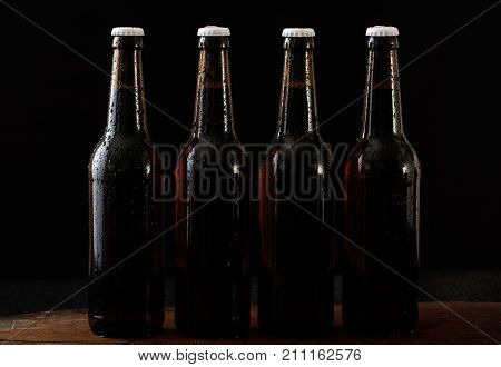 Closeup Of Four Beer Bottles Isolated On Black Background
