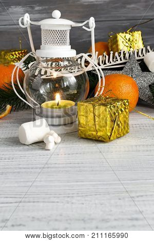 Christmas composition with candle lantern branches of a Christmas tree with tangerines and festive decorations on a white wooden background copy space