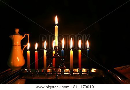 Burning Chanukah. The lit Chanukiah. Jewish holiday Hanukkah. Porcelain jug with oil