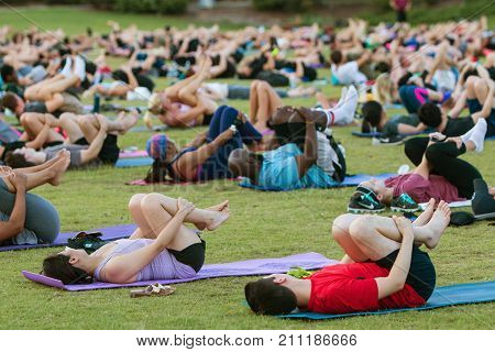 ATLANTA, GA - JULY 2017:  Dozens of people do the wind running pose on their backs as they take part in a free group yoga class at the Old Fourth Ward Park in Atlanta GA on July 2 2017.