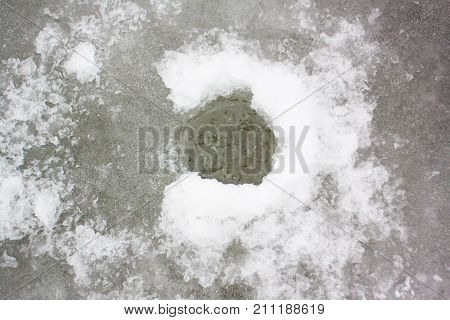 Winter ice fishing on the frozen river ice, ice fisherman on winter ice drills and fishing rod in the cold winter