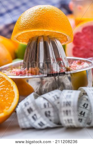 Measure Tape And Juicer With Citrus Fruits. Preparation Of Orange Grape Or Multivitamin Juice, Hands
