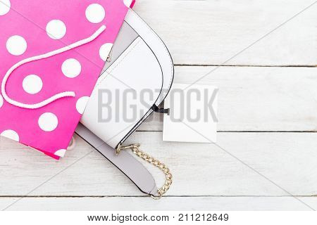 Women's light purse in a pink baket on a wooden background. Flat lay