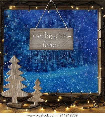 Sign With German Text Weihnachtsferien Means Christmas Holidays. Window Frame With Winter Landscape With Snow. View To Snowy Trees Outside With Snowflakes. Christmas Tree And Fairy Lights.