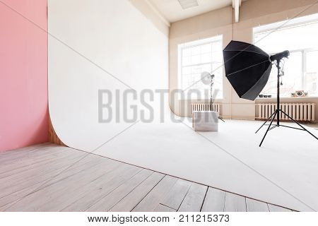 large studio space white cyclorama and natural light from large windows. professional Studio lighting equipment and flash