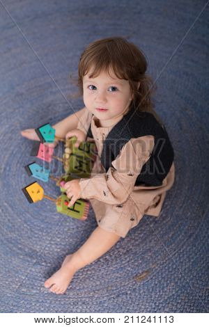 Little happy girl playing with toy on floor. Kindergarten.