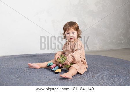 Little happy girl playing with toy on floor. Kindergarten.