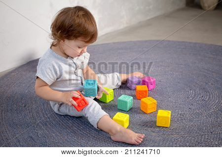 Little happy girl playing with toy on floor. Kindergarten.