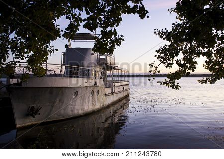 An old pleasure boat on the river in time for a beautiful sunrise. Recreation. Travels. Fishing