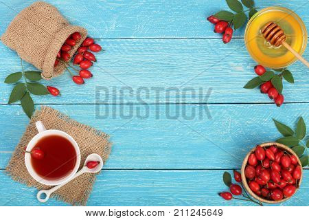 tea with rose hips and honey on blue wooden background with copy space for your text. Top view.