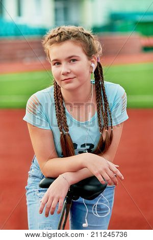 Teenage girl relaxing on a stadium.Sporty pretty teen girl loves sports.Closeup portrait of a teenage girl with a smile.outdoor stadium girl listening to music on headphones.