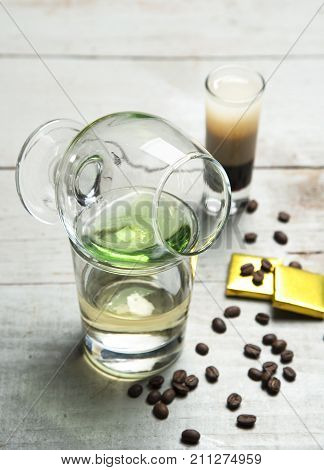 Alcohol green sambuca cocktail with coffee and chocolate on rustic wood background