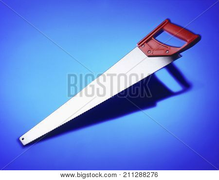 WOOD SAW CASTING SHADOW ON BLUE BACKGROUND