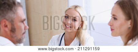 Female family doctor listen carefully young couple in office. Motherhood and child delivery ifv new life abortion therapeutist reception service physical hope emotion hospital expectation