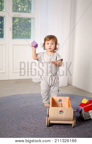 Little happy girl playing with toy on floor. Kindergarten.