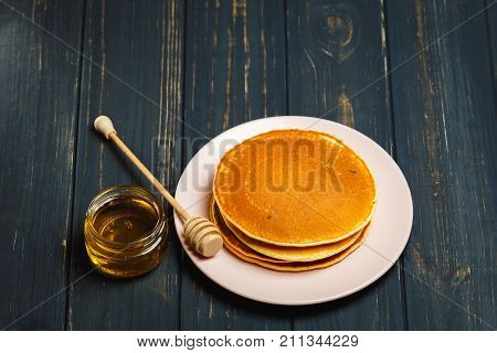 Stack of tasty pancakes with honey in jar