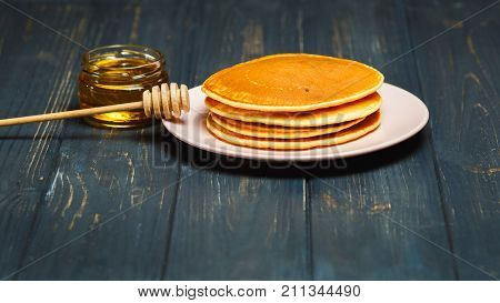 Stack of tasty pancakes with honey in jar