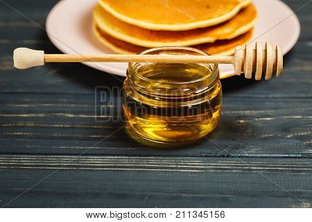 Stack of tasty pancakes with honey in jar
