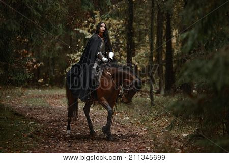 A Beautiful Warrior Girl With A Sword Wearing Chainmail And Armor Riding A Horse In A Mysterious For