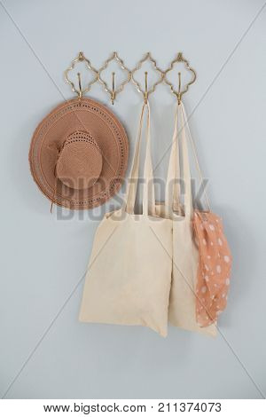 Hat, grocery bag and scarf hanging on hook against white wall
