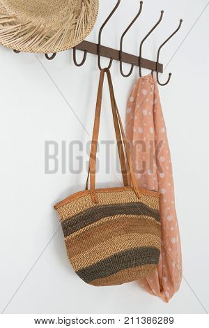 Close-up of hat, bag and scarf hanging on hook against white wall