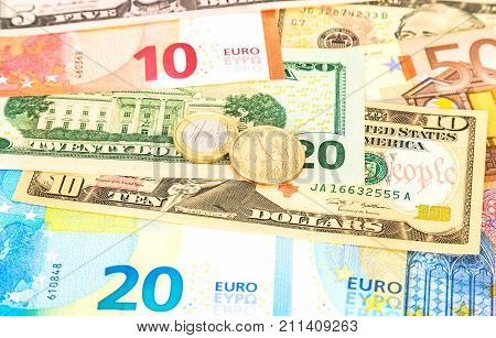 Euro and one dollar coins lying over different currency banknotes euro and dollars