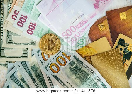money euro dollars and bitcoin with bank cards on white wooden background