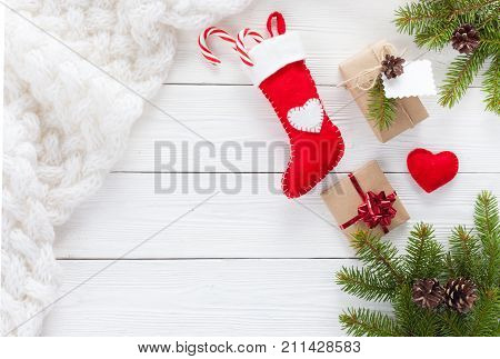 Christmas gifts and white scarf on a white wooden table with fir branches