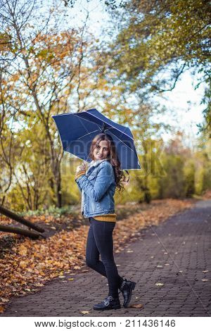 A Young Beautiful Woman Is Walking Along The Autumn Park With An Umberella In Her Hands. Autumn Port