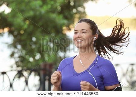Overweight young woman jogging in park. Weight loss concept