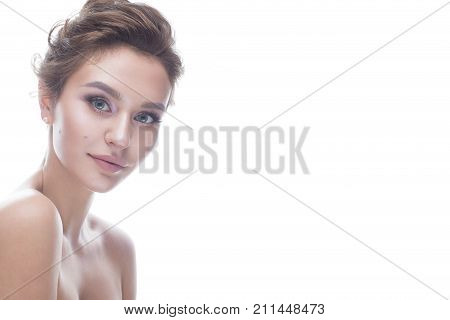 Young girl with a gentle nude makeup and hairstyle. Beautiful model with shining perfect skin. Beauty of the face. White isolated background.