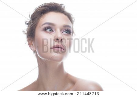 Young girl with a gentle nude makeup and hairstyle. Beautiful model with shining perfect skin. Beauty of the face. White isolated background.