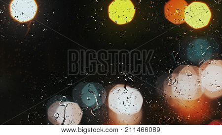 Raindrops On A Car Window With Beautifully Blurred Background Of Street Traffic Lights