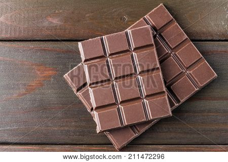 Bitter dark chocolate bar on wooden planks background top view.
