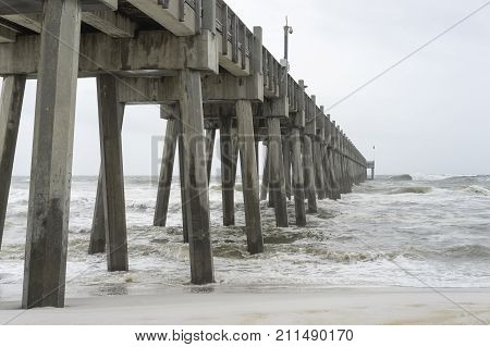 Looking up from the beach at huge concrete fishing pier in Pensacola Florida as tropical storm comes ashore.