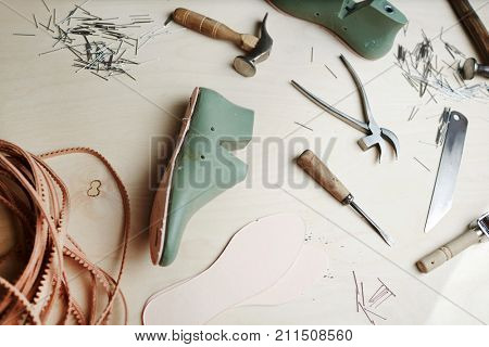 Wooden cobbler table with handtools, sole and footwear forms prepared for work