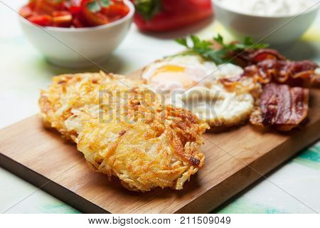 Hash browns, potato pancakes with fried egg and bacon