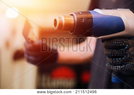 Master installs a tint film for the car glass with a hairdryer and spatula with glare of light. Concept tinting car