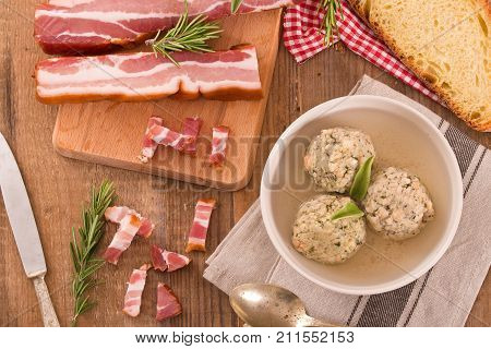 Canederli pasta with bacon and sage on wooden table.