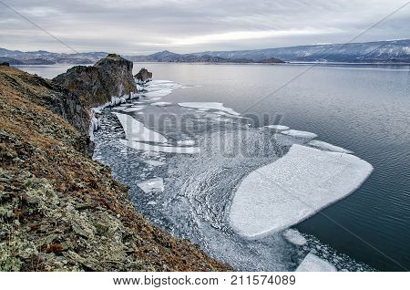 Baikal Lake and rock in the December cold. Time of freeze-up. Ice floes is swiming on the water. Siberia, Russia